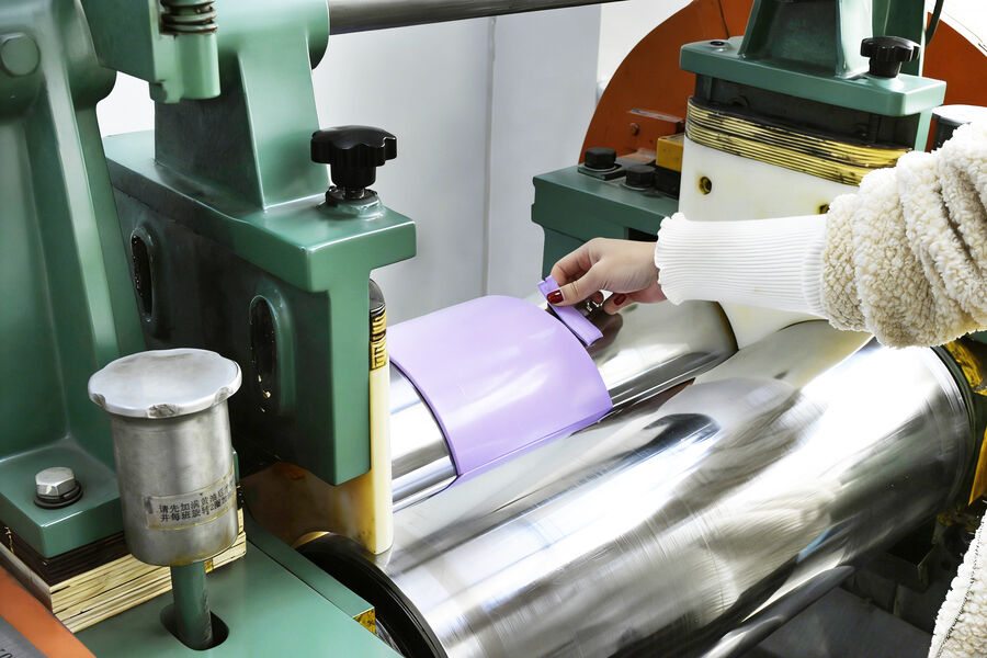 A cutting press with a sheet of coloured silicone being fed over the roller.