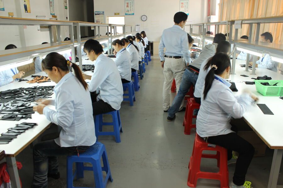 The finishing bench line, straps handled in trays along a single long table.